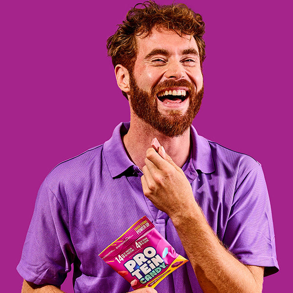 male fitness model with berry punch purple protein candy purple background